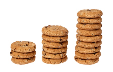 Three stacks of chocolate chip cookies in rising succession on a white background.の写真素材