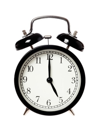 One black alarrm clock displays the time five o clock, isolated on white background.の写真素材