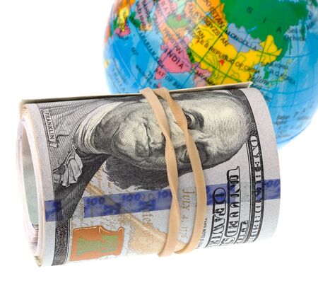 Rolled US Dollars infront of the world isolated on white background.の写真素材