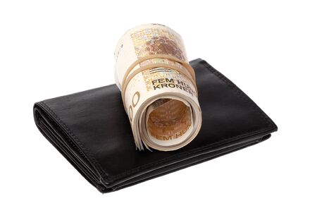 One roll Norwegian 500 Kroner banknotes on top a black wallet isolated onwhite background.