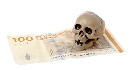 One small plastic skull on Danish 100 kroner banknote isolated on white background.の写真素材