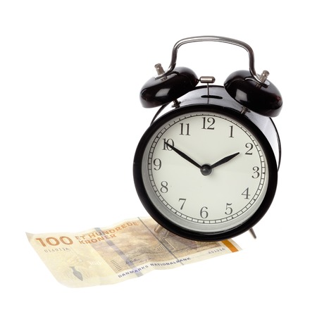 A black alarm clock with happy face on a one hundred Kroner Danish money banknote isolated on white background.の写真素材