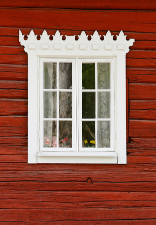 Closeup of an old Swedish red painted timber wall with a withe framed window.の写真素材