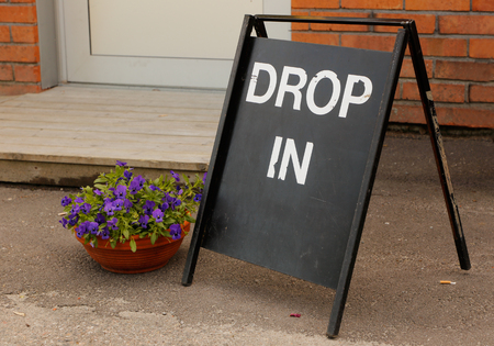 A  Drop in sign with white text onblack outside a building.の写真素材