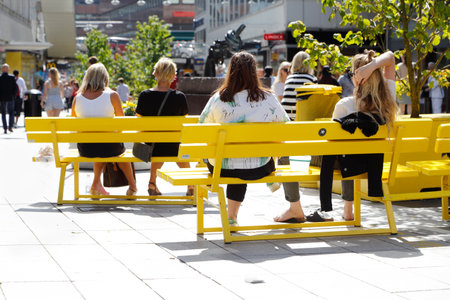 Stockholm, Sweden - August 4, 2015: Summer time at the street Sergel Arkaden in the city center off Stockholm with people sitting on yellow bench in the warm sun light.のeditorial素材