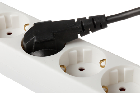 Cluse-up of a white earthed power strip with a black power plug connected to one of the sockets.の写真素材