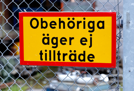 Close up of yellow sign on a fence with text in Swedish No admission for unauthorized (Obehoriga ager ej tilltrade)の写真素材