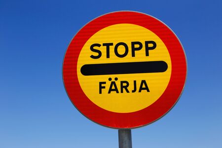 Swedish road sign stop at ferry berth against blue sky.の写真素材