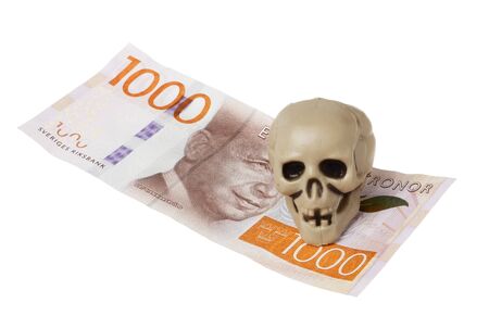 One small plastic skull on a Swedish 1000 banknote isolated on white.の写真素材