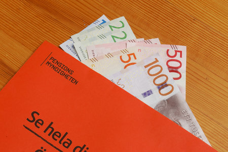 Stockholm, Sweden - March 3, 2017:The orange envelope from the Swedish Pensions Agency (Pensionsmyndigheten) with teh annual statement on top of Swedish banknotes.のeditorial素材