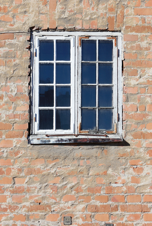 An old windows with glazing bars in a red brick wall.
