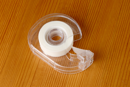 Transparent tape dispenser on a wooden table.の写真素材
