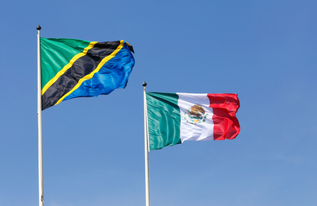 The national flags of Tanzania (left) and Mexico (right) hoisted agians a blue sky.の写真素材