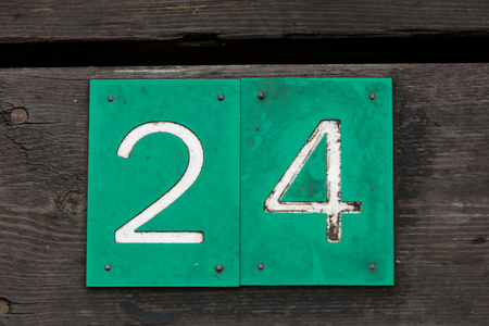 Sign with number 24 in white on green background mounted on wooden plankの写真素材