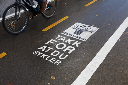 Trondheim, Norway - October 16, 2017: One bicycle passing a sign on the bicycle track with a message fromm the Tronheim enviroment project Miljopakken, with text in Norwegian translated to English reading, Thanks for cycling.のeditorial素材