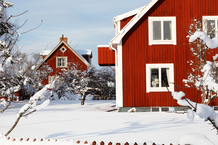 Traditional red Swedish wooden family houses surronded by snow during the winter seasonの写真素材