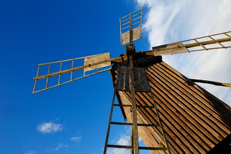 A low angle view of an old brown wooden windmill.の写真素材