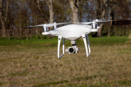 Tullgarn, Sweden - May 6, 2018: One white DJI Phantom 4 quadcopter with its camera pointing forward hovering near ground level.のeditorial素材