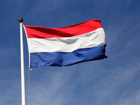 The national flag of the Netherlands flies in the wind agianst a blue sky.の写真素材