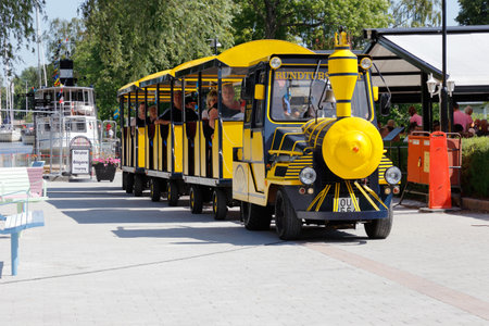 Soderkoping, Sweden - June 28, 2018: A yellow trackless sighseeing train pulled by a Kalmar Motor TA 900  with three carts attached at Kanalplan square.のeditorial素材