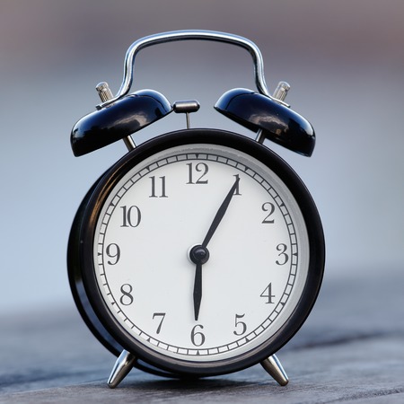 Close-up of an retro styled black alarm clock displaying five past six.の写真素材