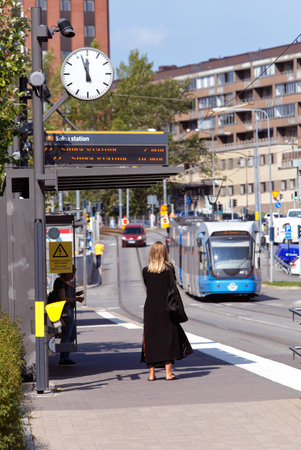 Solna, Sweden - August 24, 2018: A woman in black dress waiting for a tram ath the tram stop Solna Business Park.のeditorial素材
