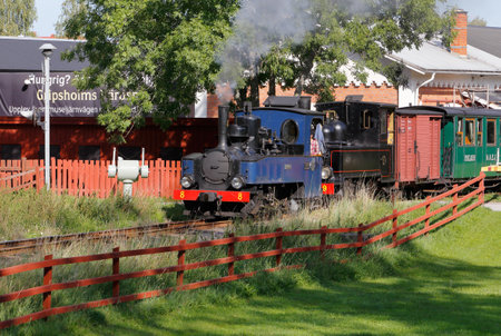 Mariefred, Sweden - September 2, 2018: Vintage narrow gauge steam train in service for the Ostra Sodermanlands museum railway has left the Maiefrd station with two steam locomotives heading for Laggesta station.のeditorial素材