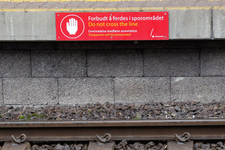 Oslo, Norway - June 20, 2019: Do not cross the line sign, crossing the railroad track is forbidden, text in in Norwegian and English.のeditorial素材
