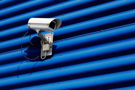 Security camera mounted on blue wall of corrugated sheet.の写真素材