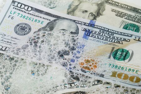 Full frame image of US dollars banknotes in various denominations in soap water.の写真素材