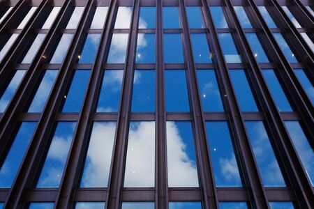 Low angle view of a modern office building with facade of glass and outside steel beams with the sky...