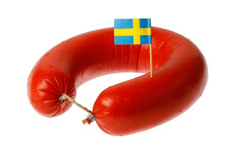 Swedish traditional falukorv sausage with attached decorative Swedish flag, isolated on white background.の写真素材