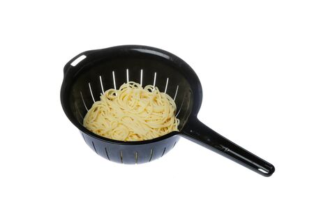 Black plastic colander filled with spaghetti isolated on white background.の写真素材