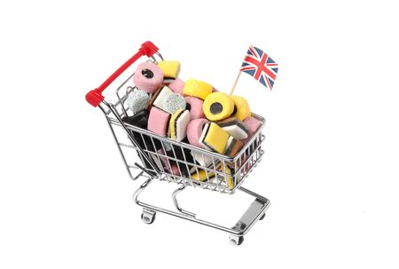 Shopping cart decorated with a British flag and filled with assorted licorice candy isolated on white background.の写真素材
