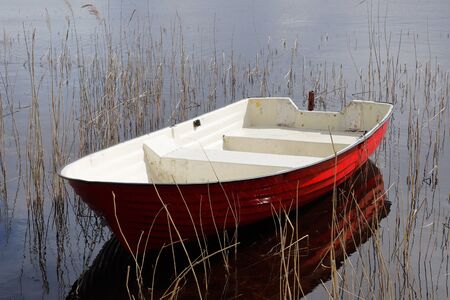Red and white plastic rowing boat without oars.の写真素材