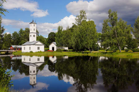 The old fire station in Stjarnsund which is located in  the Swedish province of Dalarna is reflected in the hydroelectric power plant's dam in the foreground.の写真素材