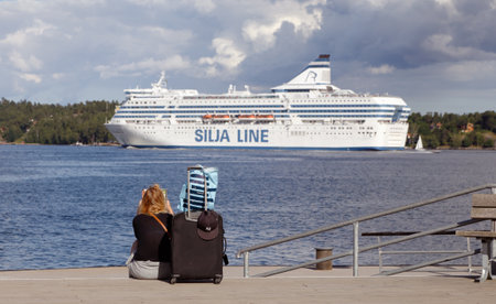 Lidingo, Sweden - July 4, 2016: A woman is sitting on the quayside waiting for the boat with her...