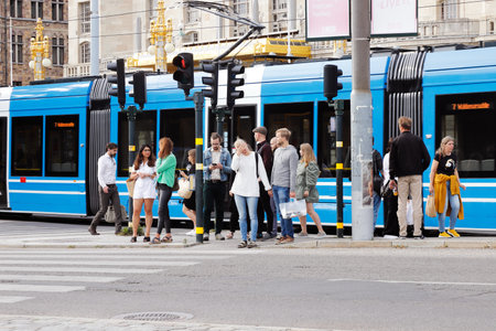 Stockholm, Sweden - July 24, 2020: At Nybroplan square people are waiting for the light become green at the crosswalk with a tram behind them.のeditorial素材