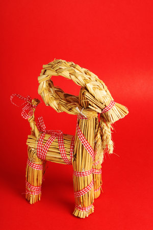 High angle view of a traditional straw Christmas billy goat on red background.の写真素材