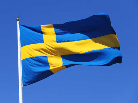 Close-up view of the Swedish flag vawing against a blue clear sky.の写真素材