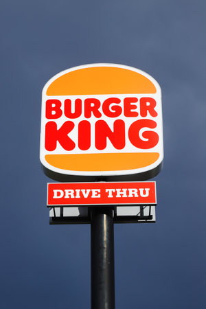Eskilstuna, Sweden - May 17, 2021: Low angle view of the new rebranded Burger King logo on a pole outside the restaurant with drive thru isolated against a dark sky.のeditorial素材