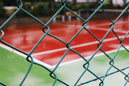 Tennis court behind fence with focus on the foreground.の写真素材