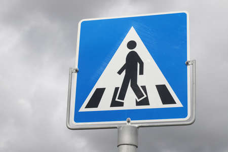 Low angle view of a norwegian pedestrian crossing road sign against clody sky.の写真素材