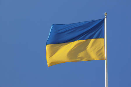 Close-up view of the Ukraine national flag against a blue clear sky.