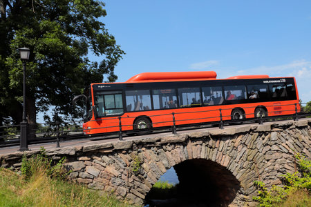Karsltad, Sweden - July 20, 2022: Red  M.A.N city bus crossing the old 17th century stone arch East bridge.のeditorial素材
