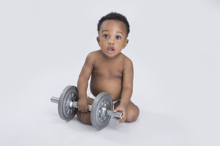 cheerful baby boy playing with a dumbbellの写真素材