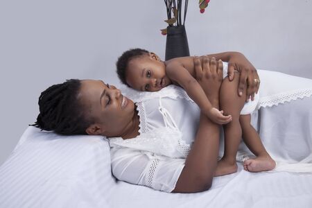 A beautiful mother carrying her baby on her chest while lying down on the bed