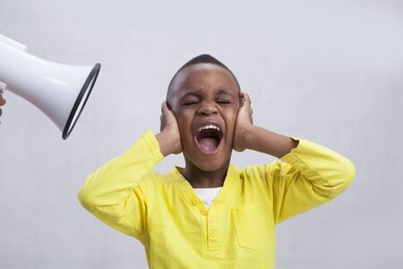 Little boy covering his ears from isolated hand holding loud megaphoneの写真素材