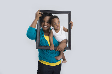 A woman carrying her baby and holding a picture frame の写真素材