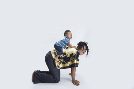 A beautiful young lady bending  and carrying her son piggybackの写真素材